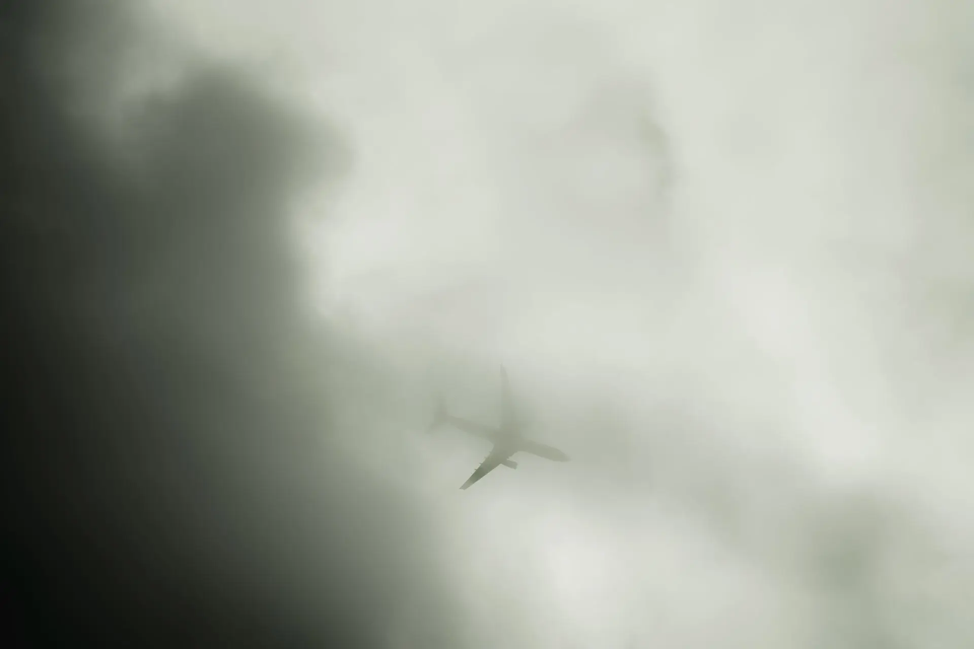 Its A Plane A plane flies through cloud cover in black and white